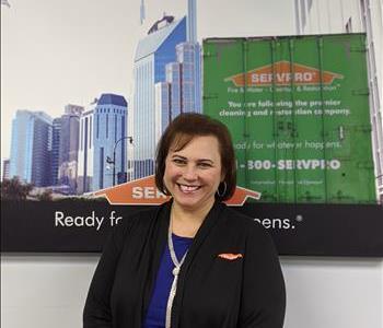 SERVPRO of Jersey City shares picture of one of their female project managers smiling and standing in front of a SERVPRO Ad.